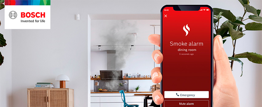 Bosch Smart Home App zeigt Rauchmelder-Benachrichtigung aus Esszimmer mit Notruf-Taste und Rauch aus Küche im Hintergrund