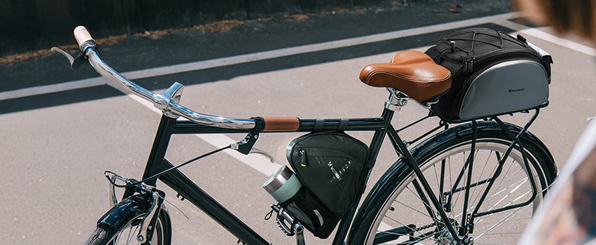 Vintage-Fahrrad mit Wozinsky Satteltasche und Rahmentasche auf sonniger Straße geparkt – Fahrradzubehör für Touren