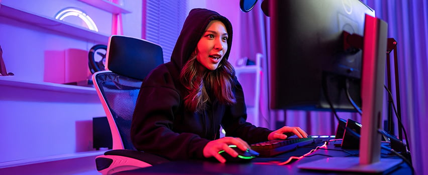 Junge Frau zockt am Computer mit Wozinsky Gaming-Maus und Tastatur in dunklem Raum mit lila RGB-Beleuchtung