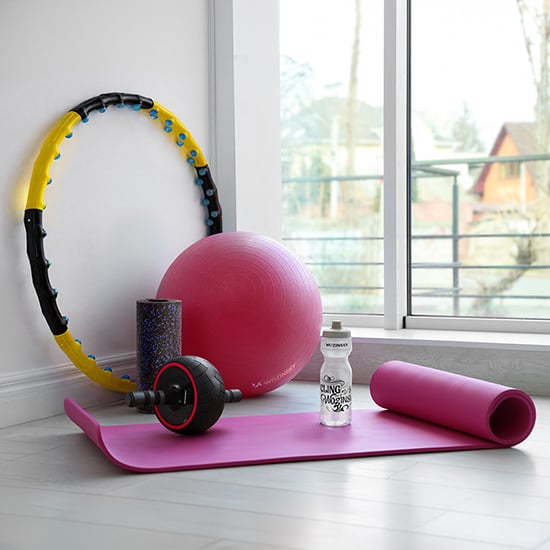 Wozinsky Sport- und Fitnessausrüstung mit pinker Yogamatte, Ball, Hula-Hoop-Reifen, Schaumstoffrolle und Trinkflasche am Fenster