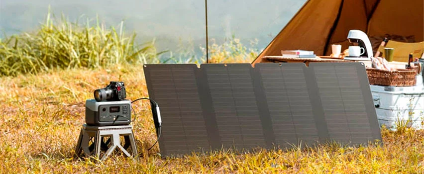 EcoFlow RIVER 2 Powerstation und Solarpanel aufgestellt neben einem Zelt auf einer Wiese – kompakte Off-Grid-Energielösung zum Campen